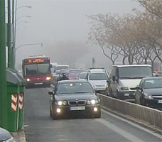 Tráfico en una avenida bajo la niebla de una mañana en Sevilla