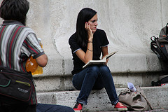 Chica sentada en una escalera en posición de pensar con un libro abierto