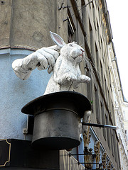 Mano sacando un conejo de una chistera en una pared